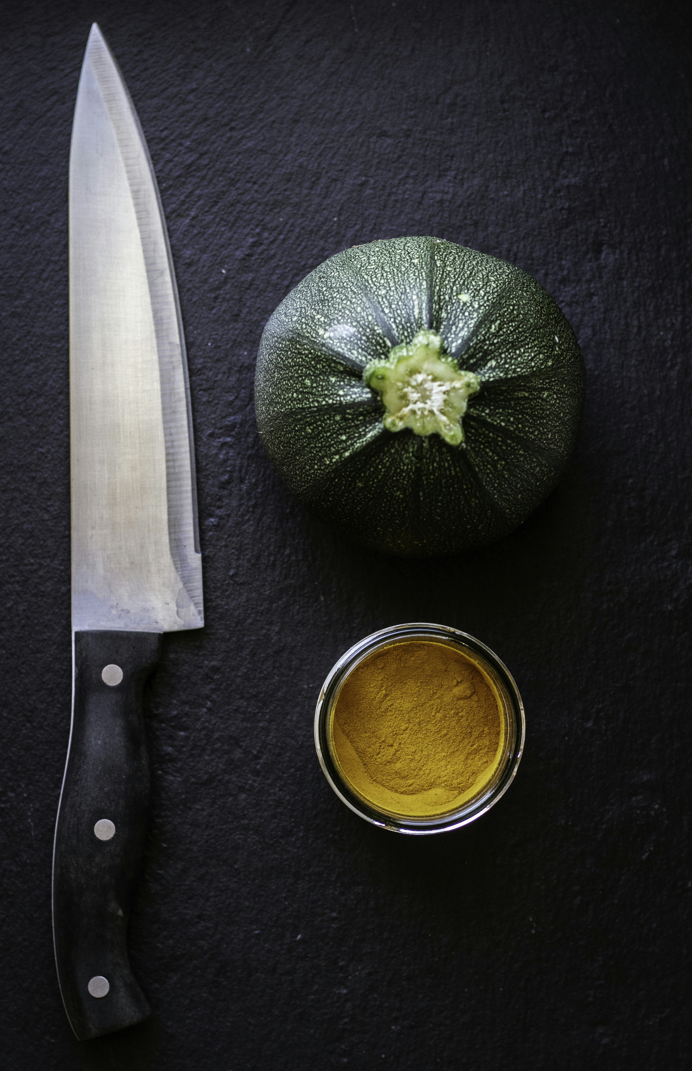 black handled knife beside green vegetable